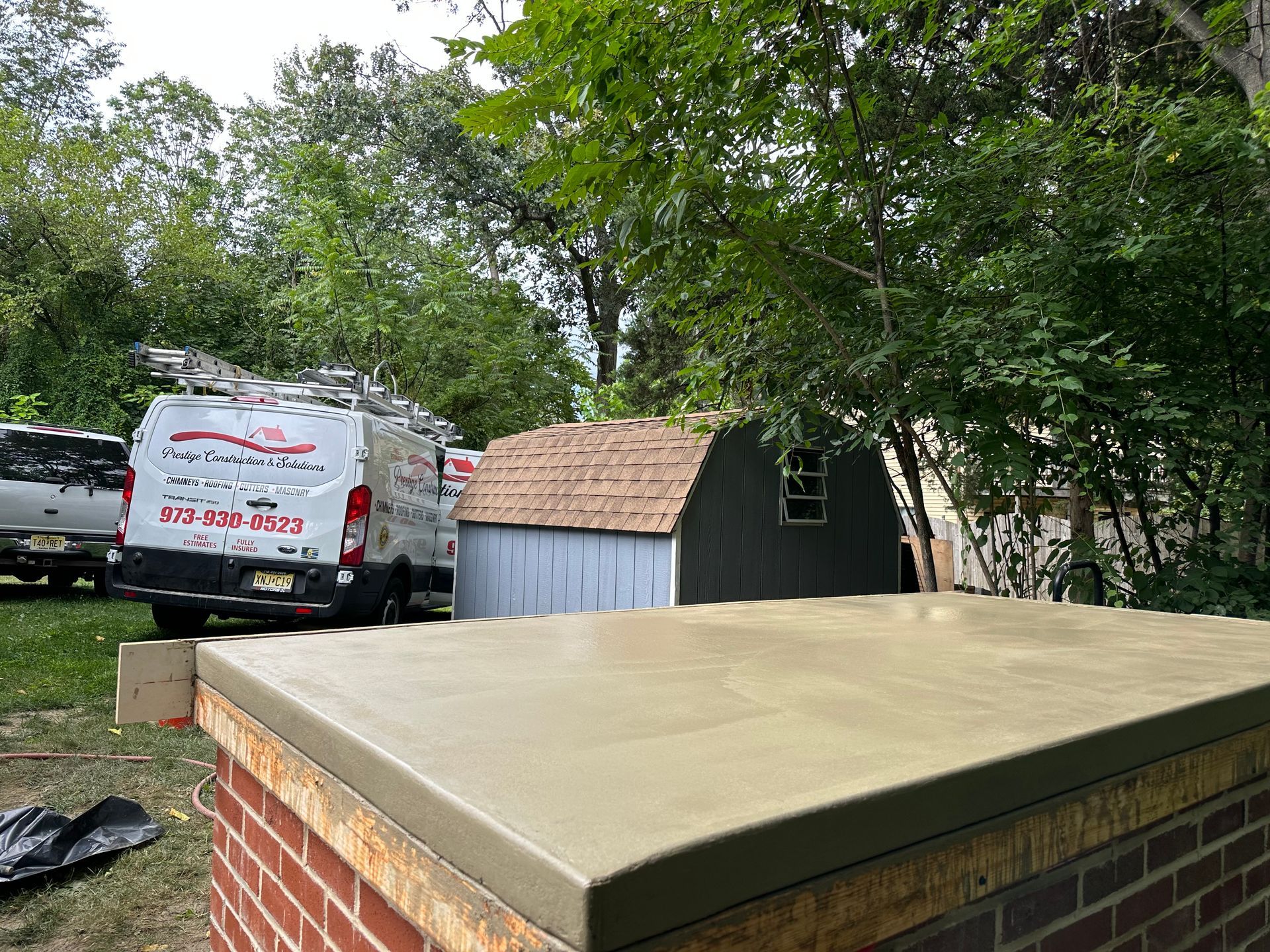 A white van is parked on the side of a brick wall.