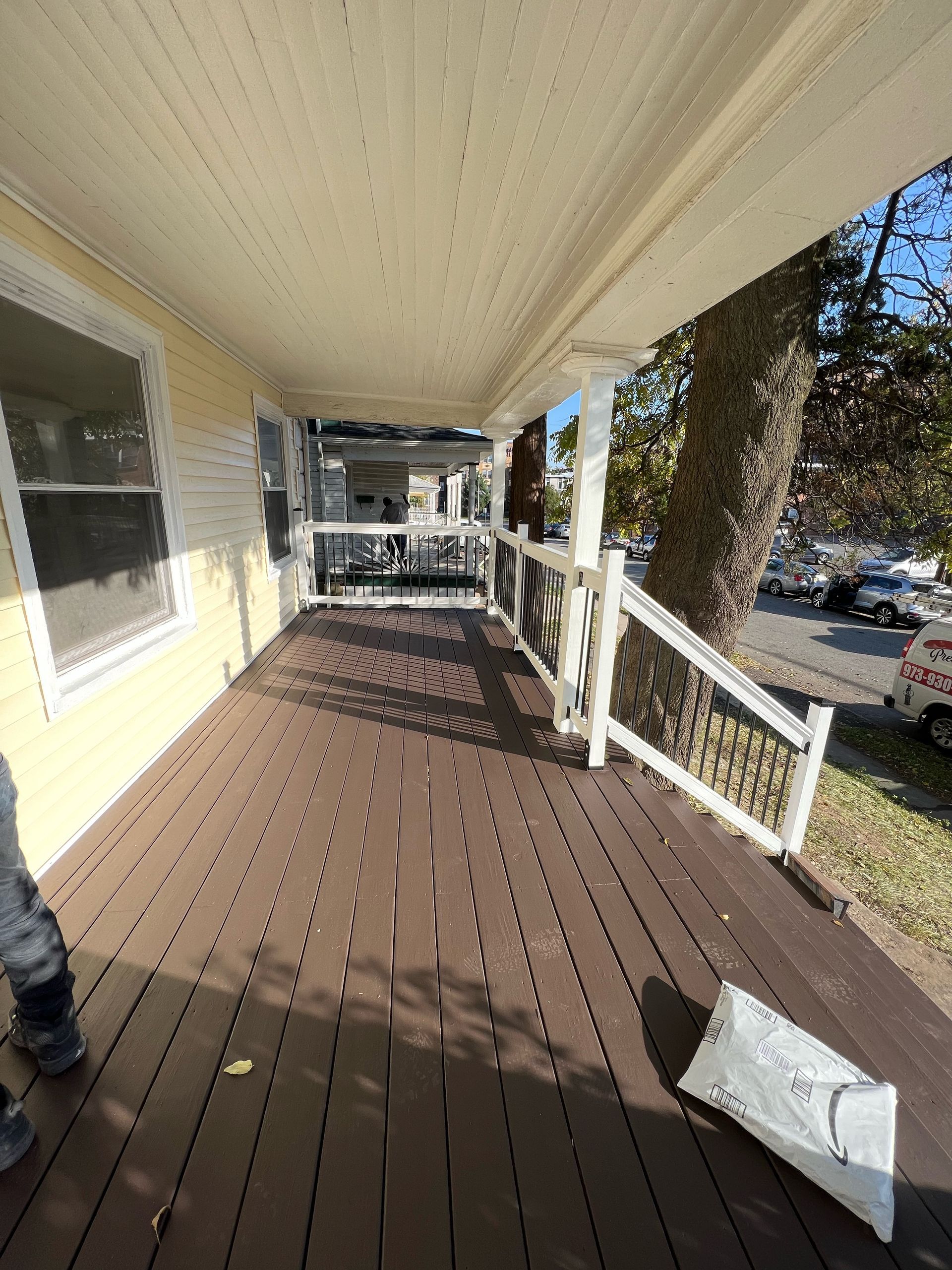 A porch with a wooden deck and a white railing.