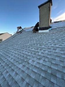A man is working on the roof of a house with a chimney.