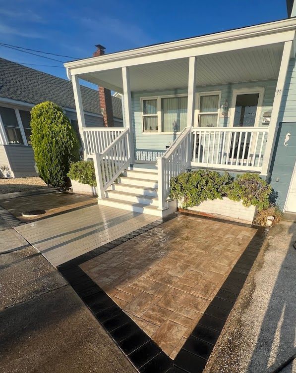 A house with a porch and stairs and a concrete patio in front of it.