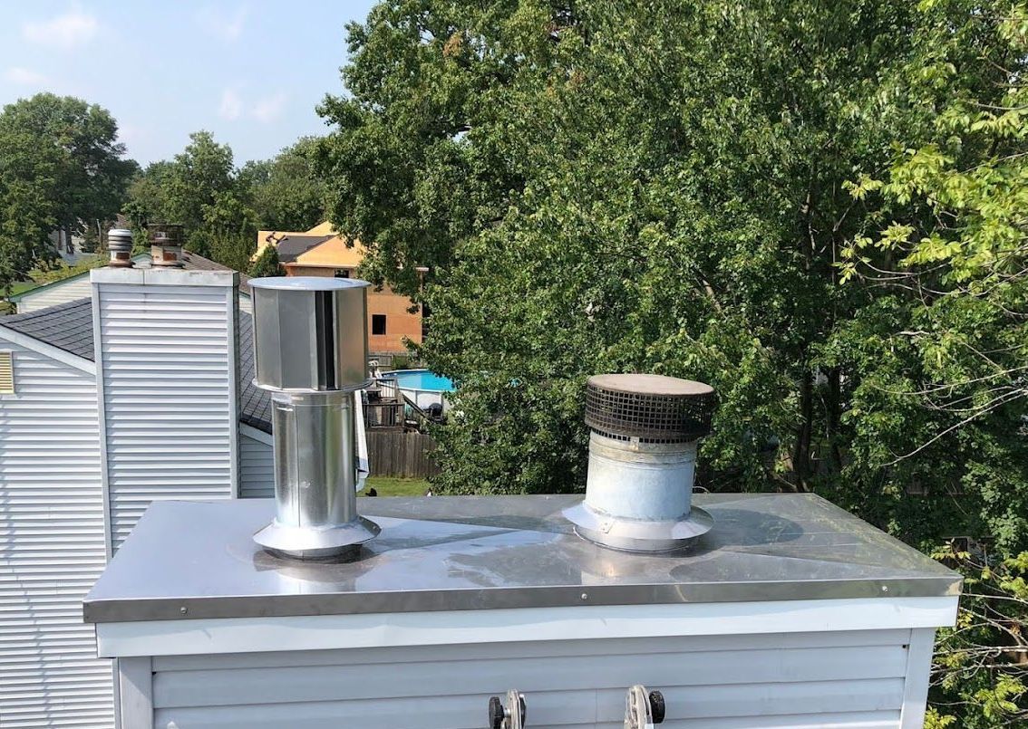 A chimney on top of a building with trees in the background.