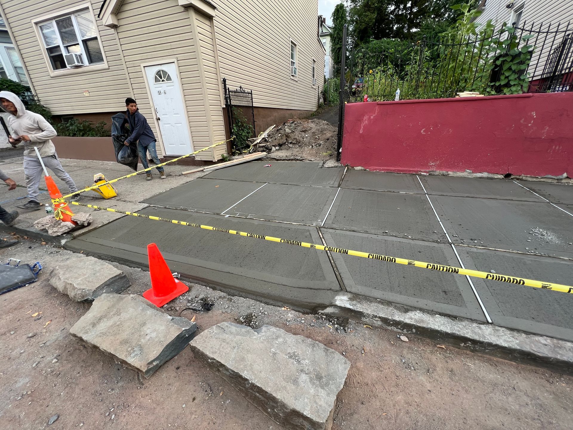 A group of construction workers are working on a concrete driveway.