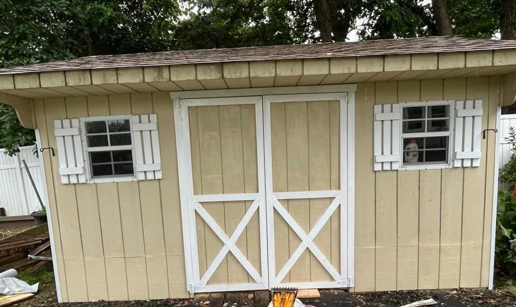A small wooden shed with white doors and windows.