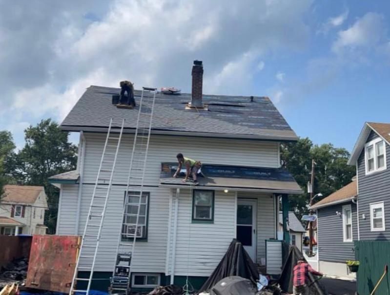 A group of people are working on the roof of a house.