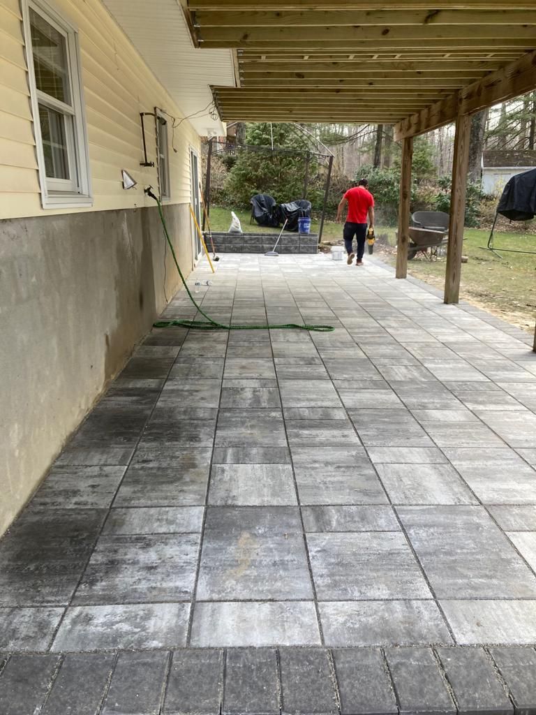 A man is walking down a patio under a wooden deck.