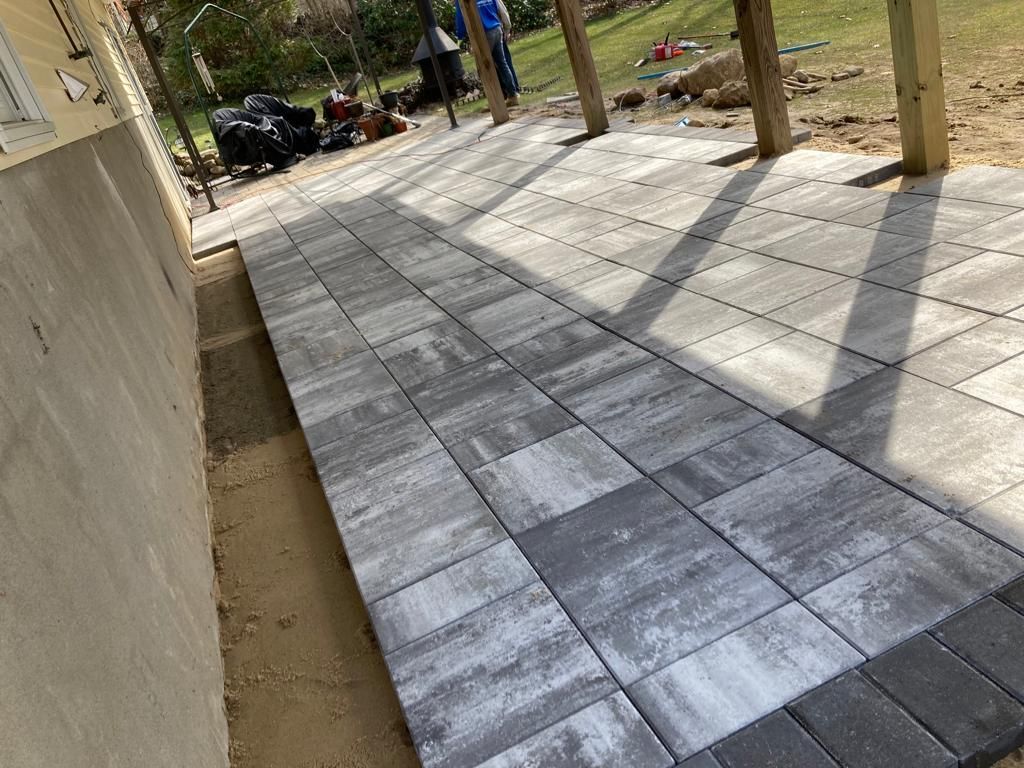 A brick walkway is being built next to a building.