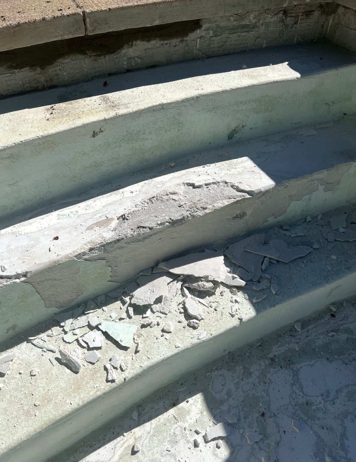 Close-up of damaged concrete outdoor stairs with crumbling edges and debris scattered on the steps.
