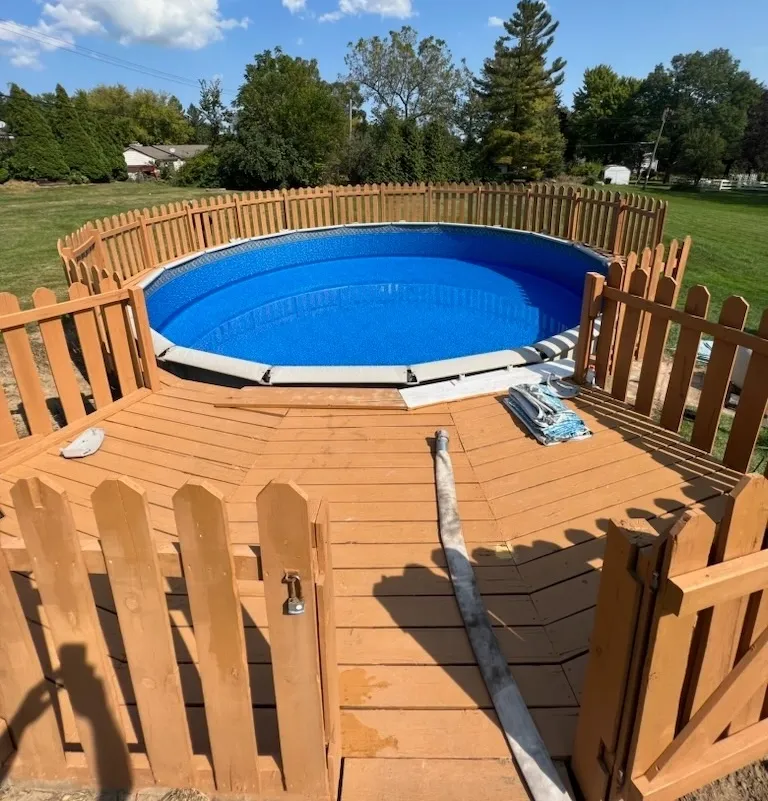 A large blue pool is surrounded by a wooden fence