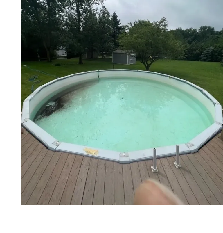 A large swimming pool with a wooden deck in front of it