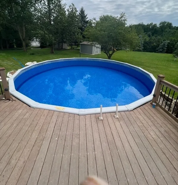 A large round swimming pool is on a wooden deck