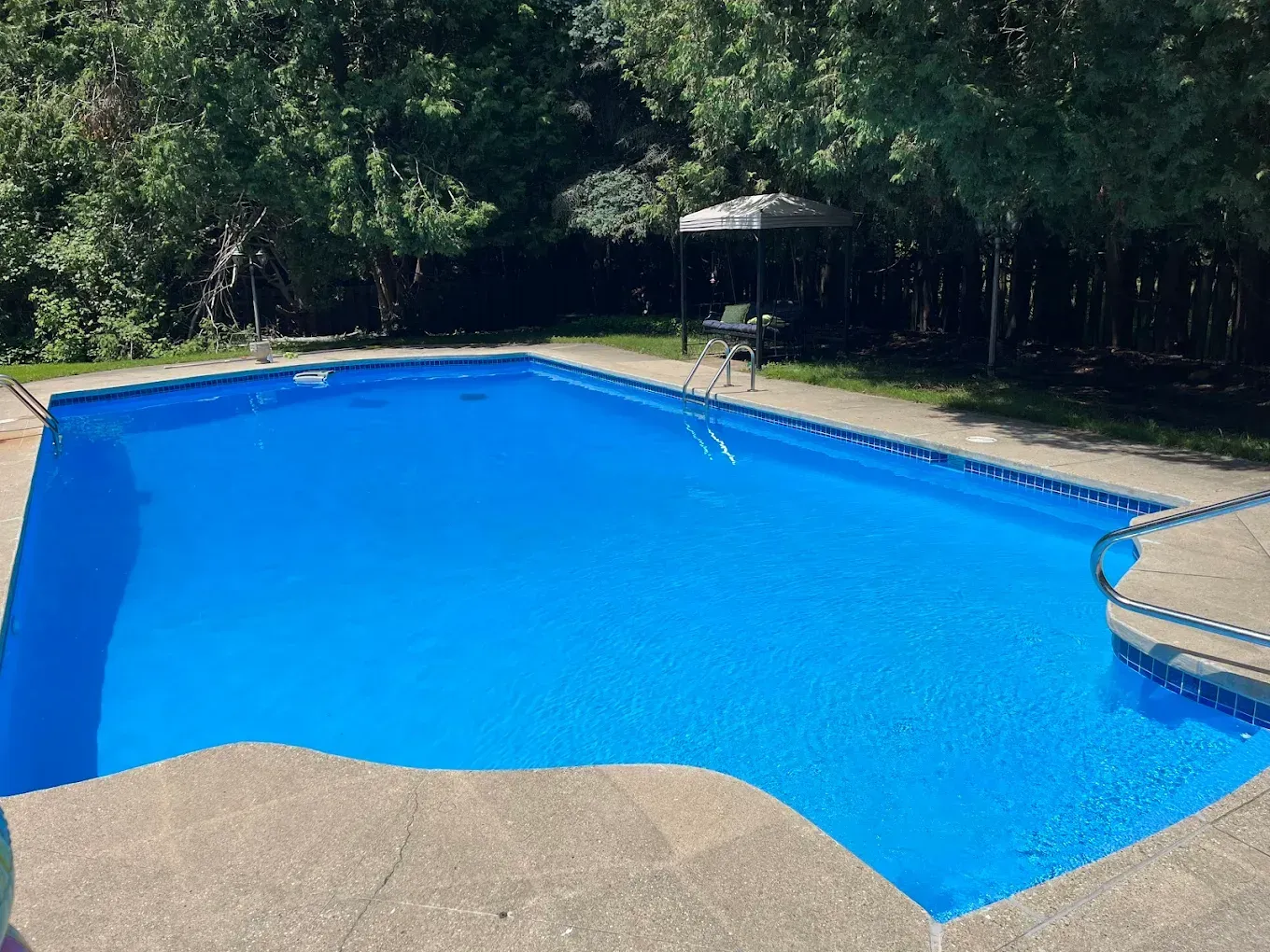 A woman is sitting in a swimming pool with her feet in the water.