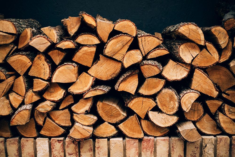 A pile of logs stacked on top of each other on a brick wall.