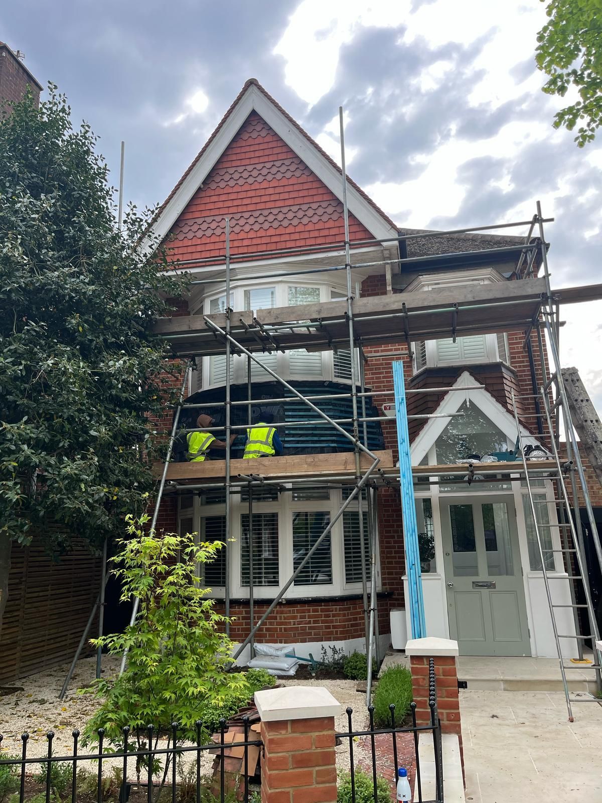 A brick house with scaffolding around it is being remodeled.