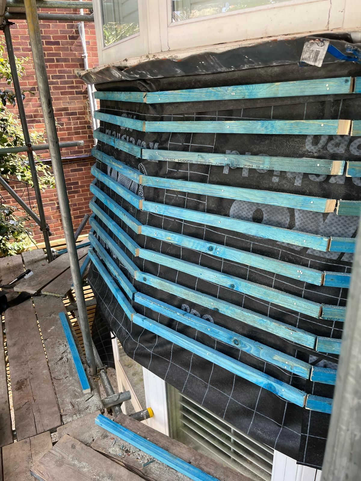 A building with a lot of blue bars on it is being built.
