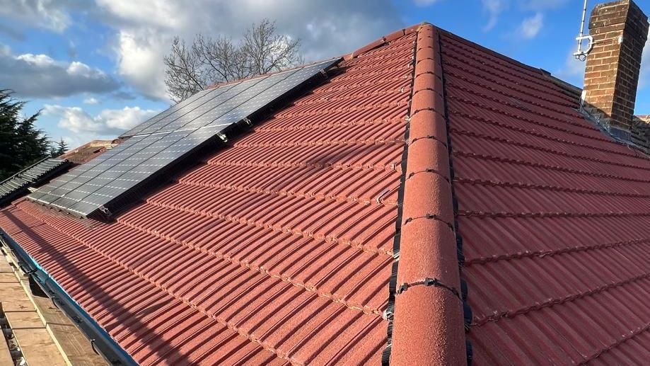 A red tiled roof with solar panels on it.