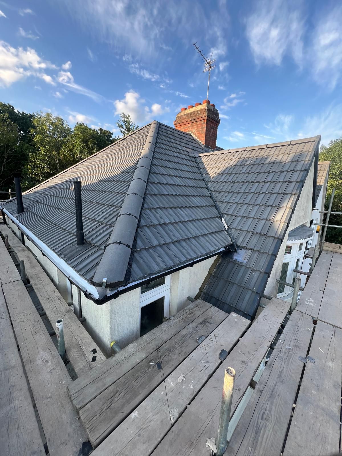 A house with a tiled roof is sitting on top of a wooden scaffolding.