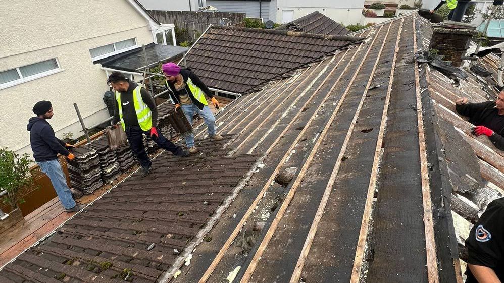 A group of people are working on the roof of a house.