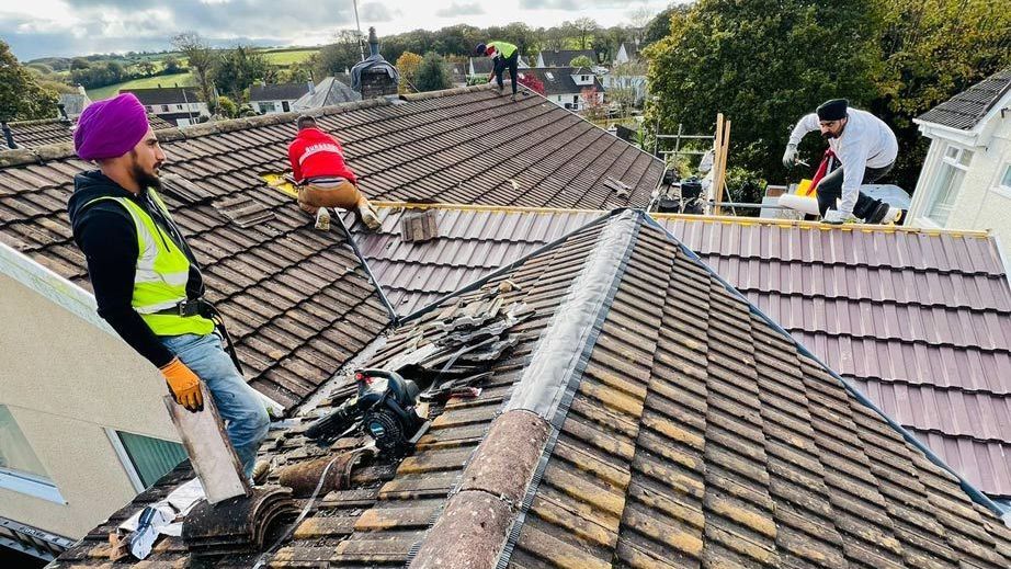 A man is sitting on top of a tiled roof.