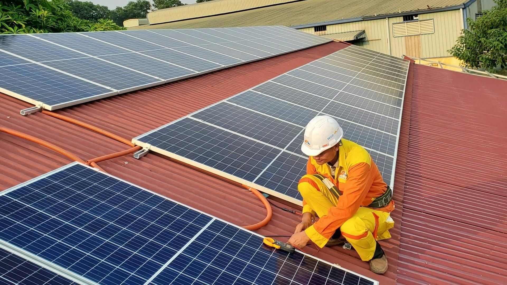 A man is installing solar panels on the roof of a building.