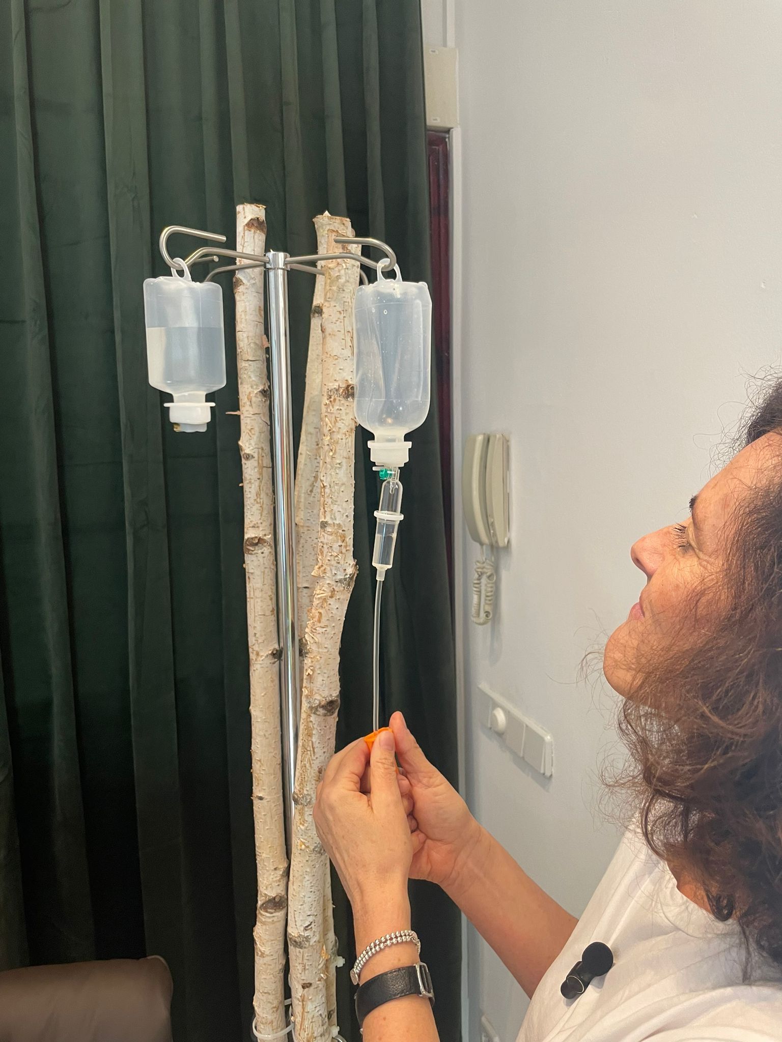 Eine Frau steht vor einer Lampe, an der Infusionsbeutel hängen.