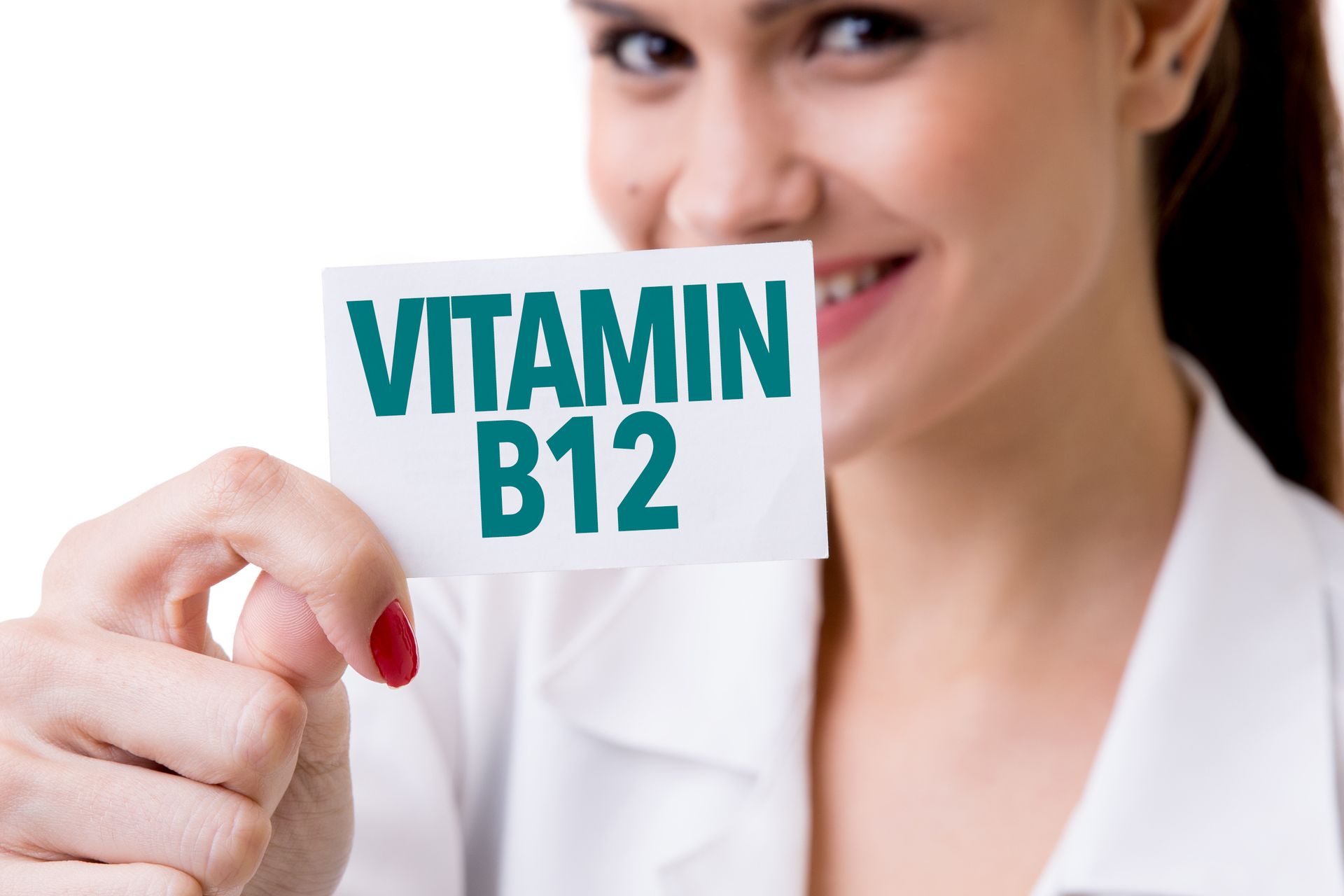 Eine Frau hält eine Karte mit der Aufschrift „Vitamin B12“.