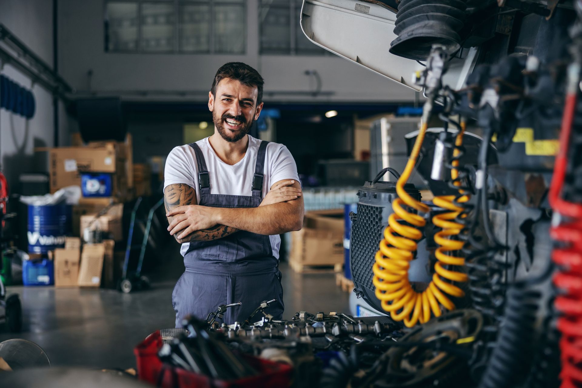 A smiling worker in blue overalls standing next to a vehicle to add a tow behind motor attachment. A smiling worker in blue overalls standing next to a vehicle to add a tow behind motor attachment.