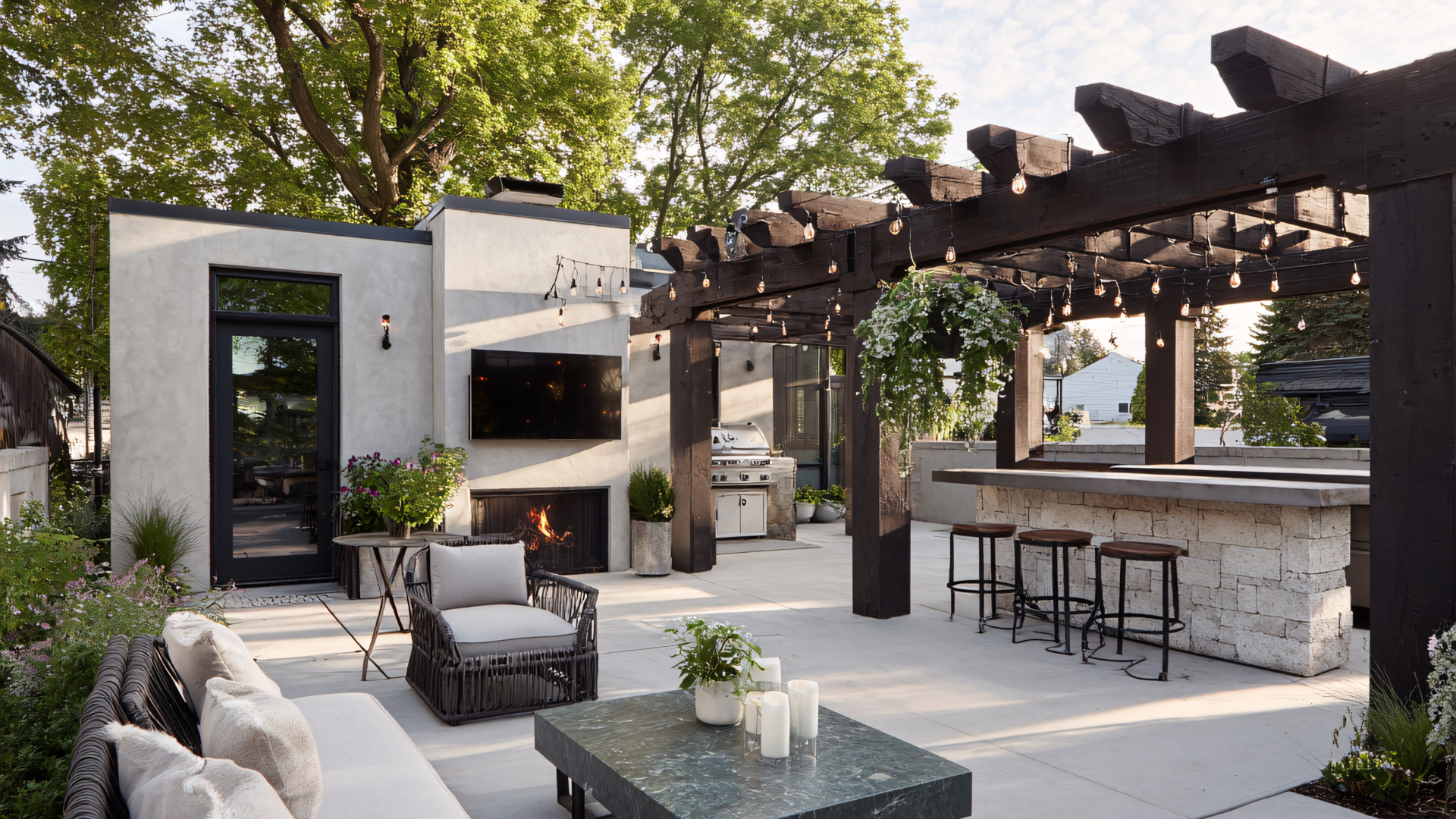 Outdoor patio with fireplace, pergola, and bar, featuring seating, lights, and greenery.