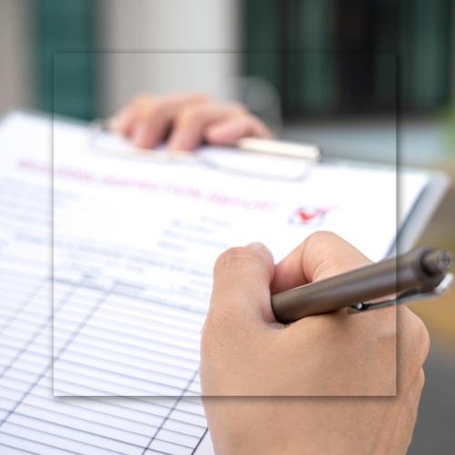 Person writing on a clipboard with a pen; outdoors, document in focus.