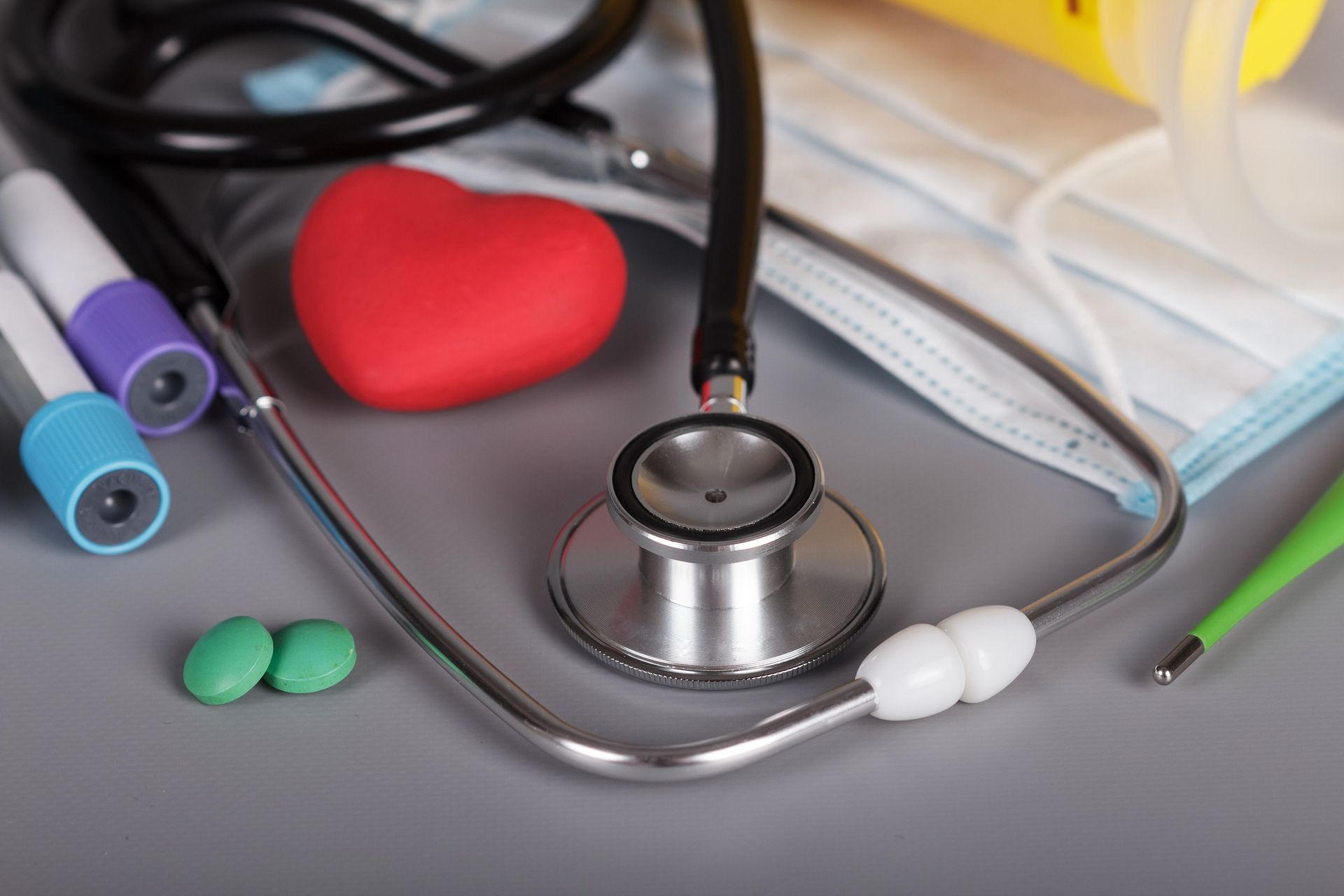 A stethoscope is sitting on a table next to a red toy heart.