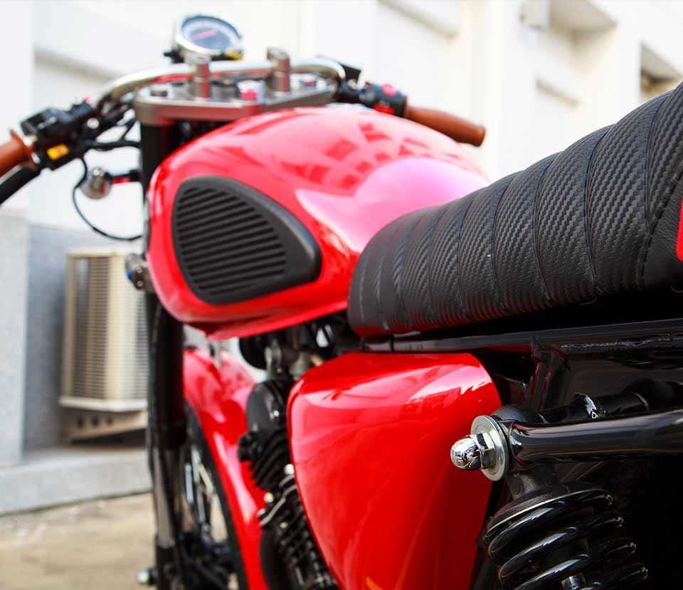 A red motorcycle with a black seat is parked in front of a building