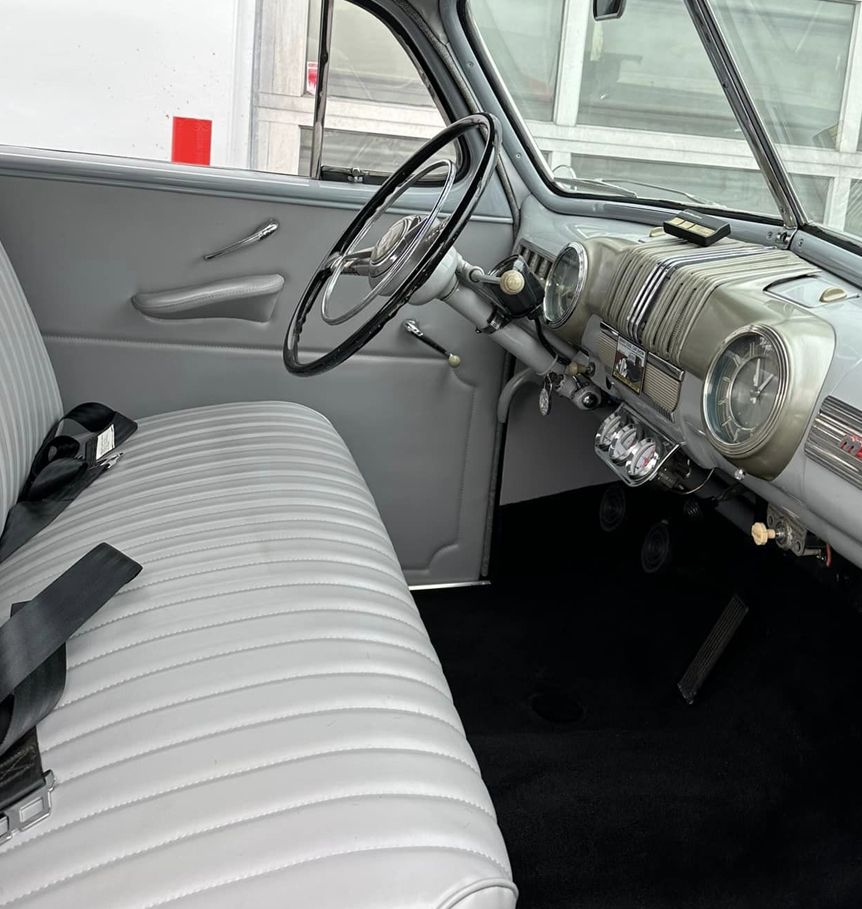 The interior of an old car with a white seat and steering wheel