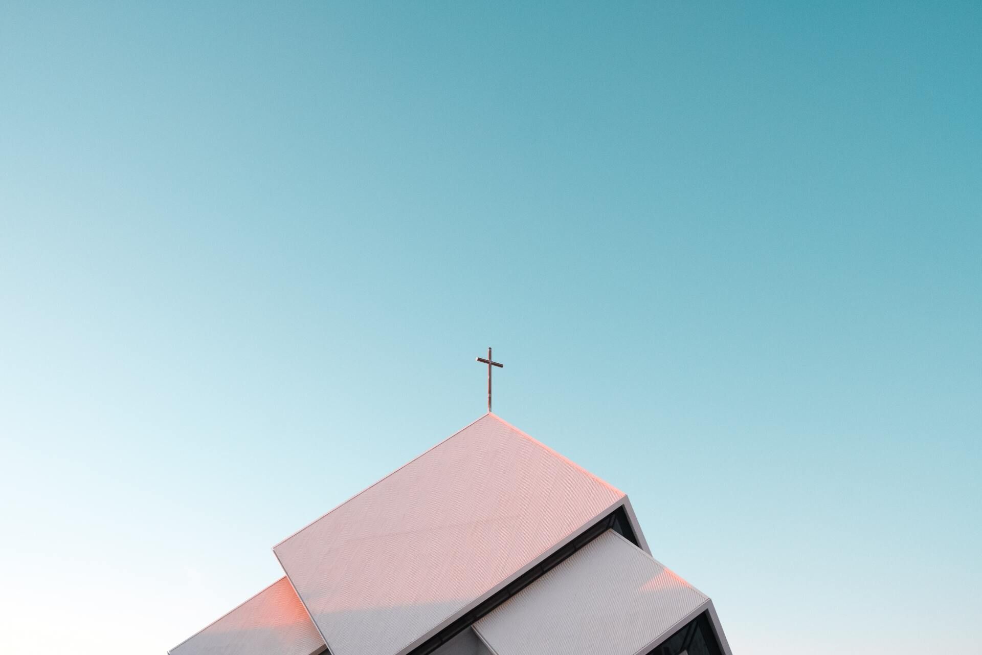 A church with a cross on top of it against a blue sky.