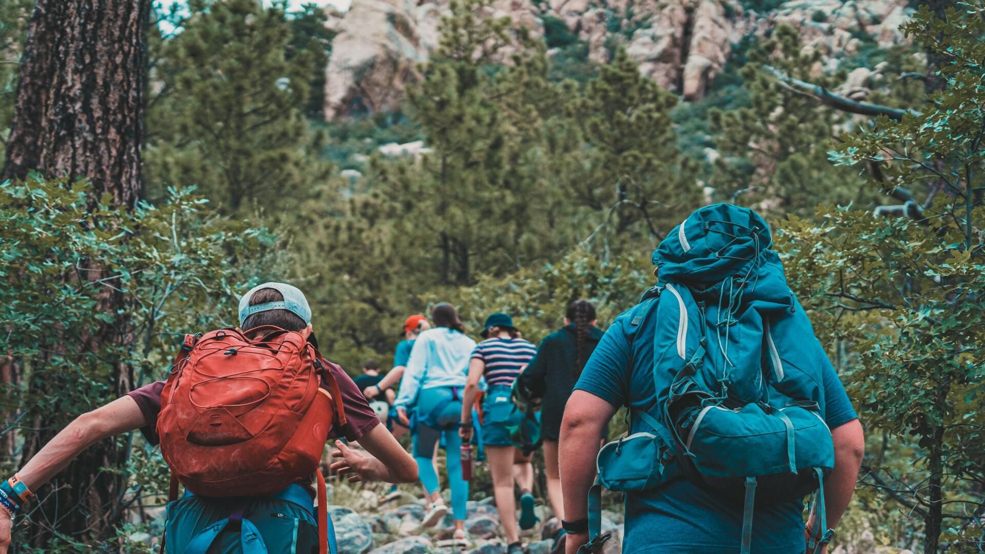 A group of people with backpacks are hiking up a mountain.