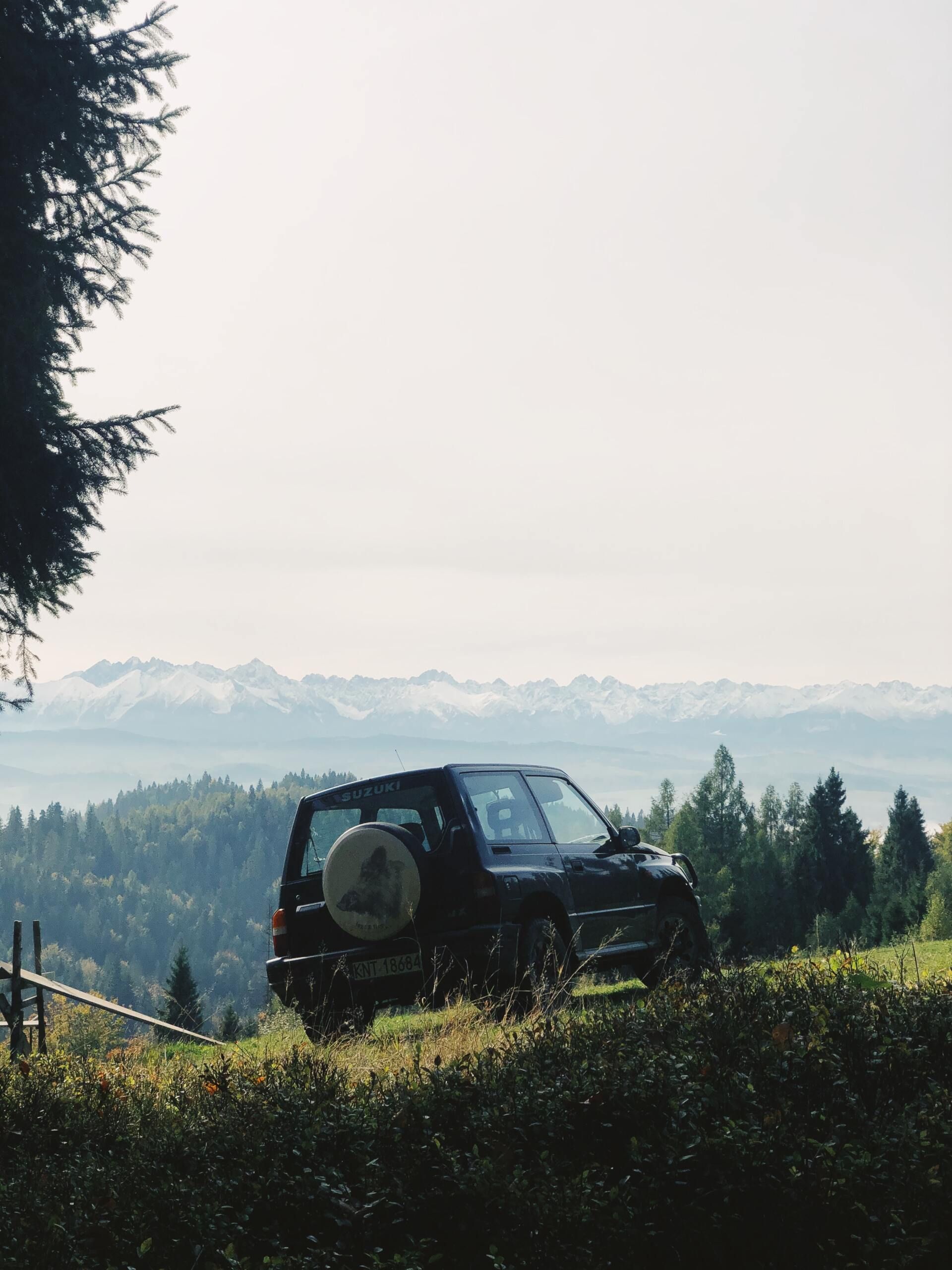 A black suv is parked on a hill with mountains in the background