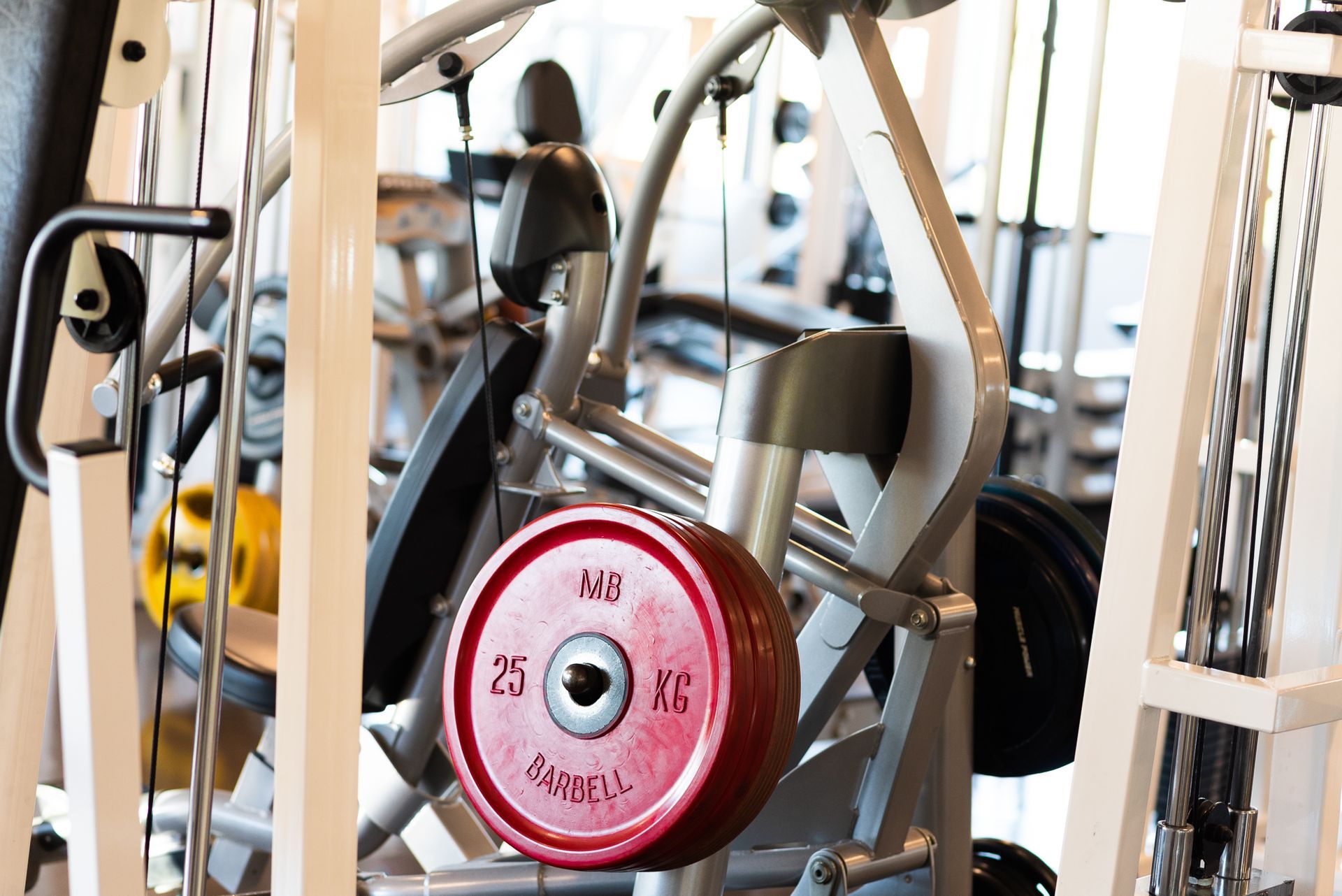 Een rode gewichtsschijf hangt aan een machine in een sportschool.