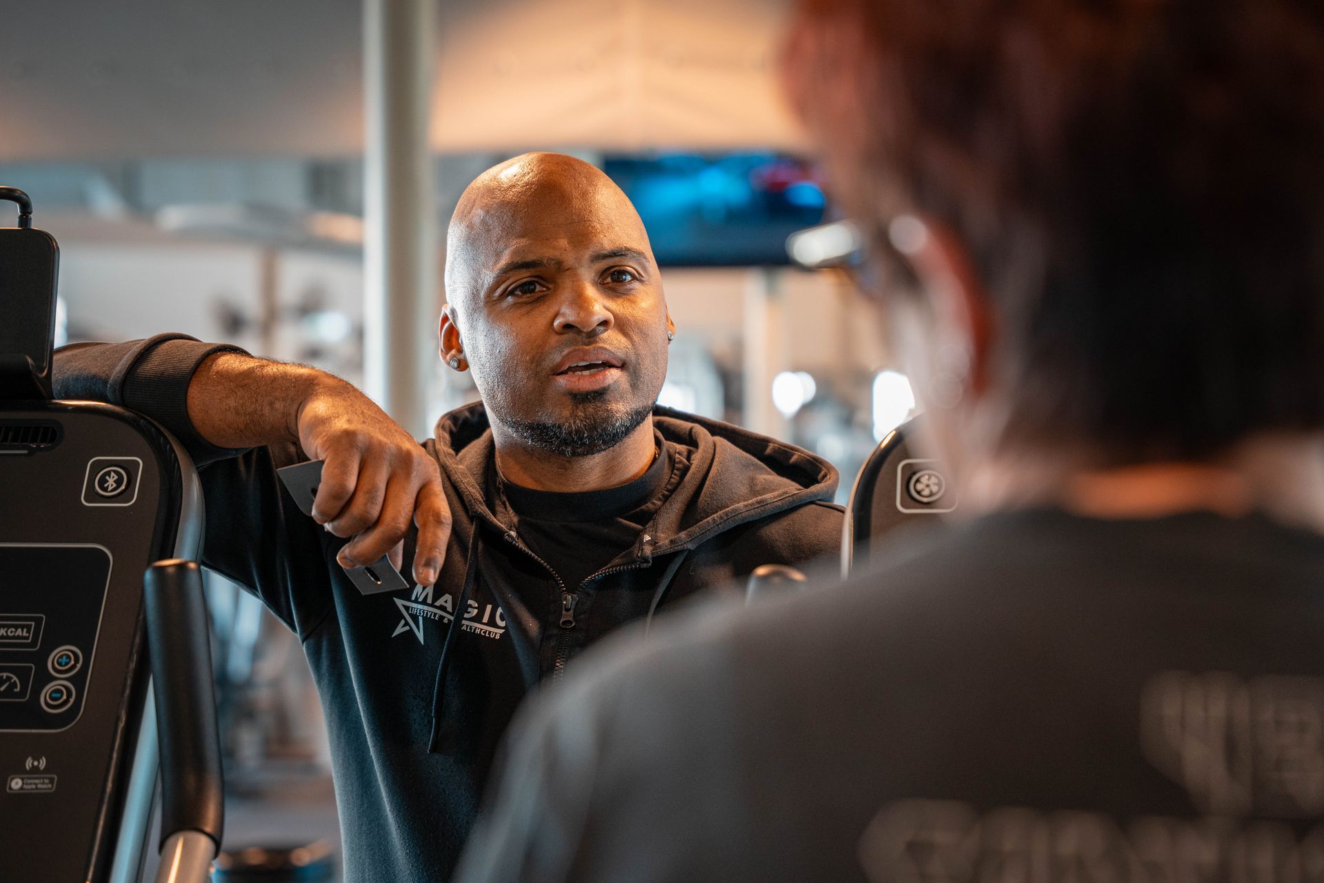 Een man praat met een andere man in de sportschool.