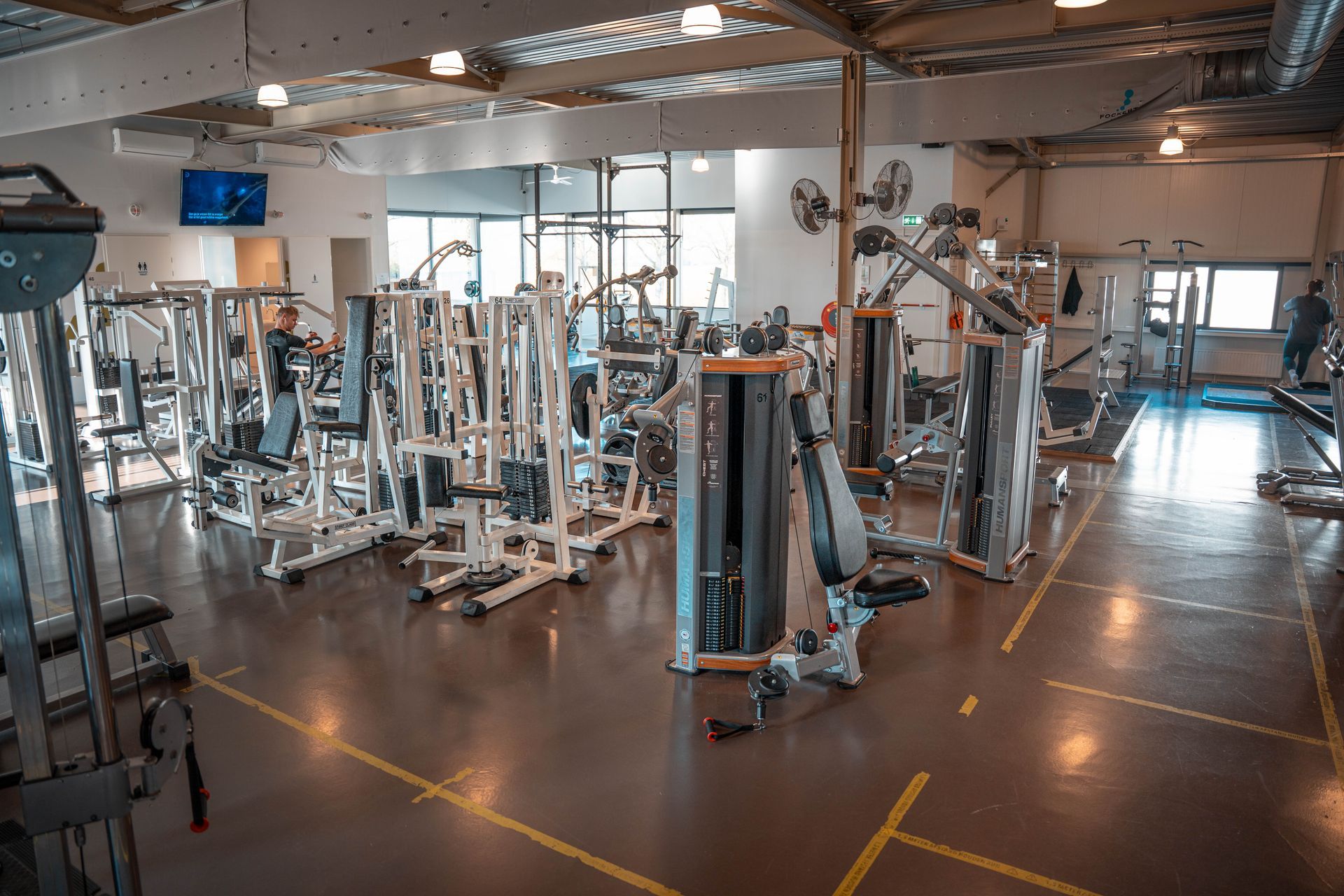 Een grote sportschool vol met fitnessapparatuur.