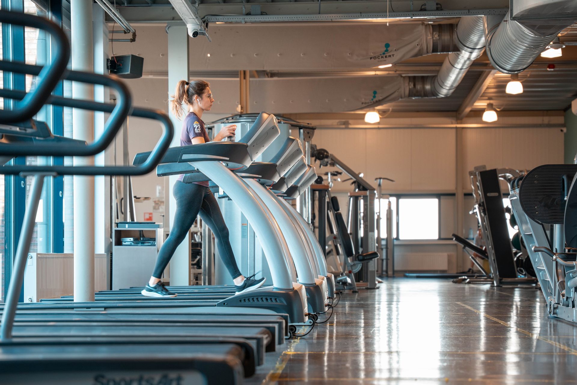 Een vrouw rent op een loopband in een sportschool.