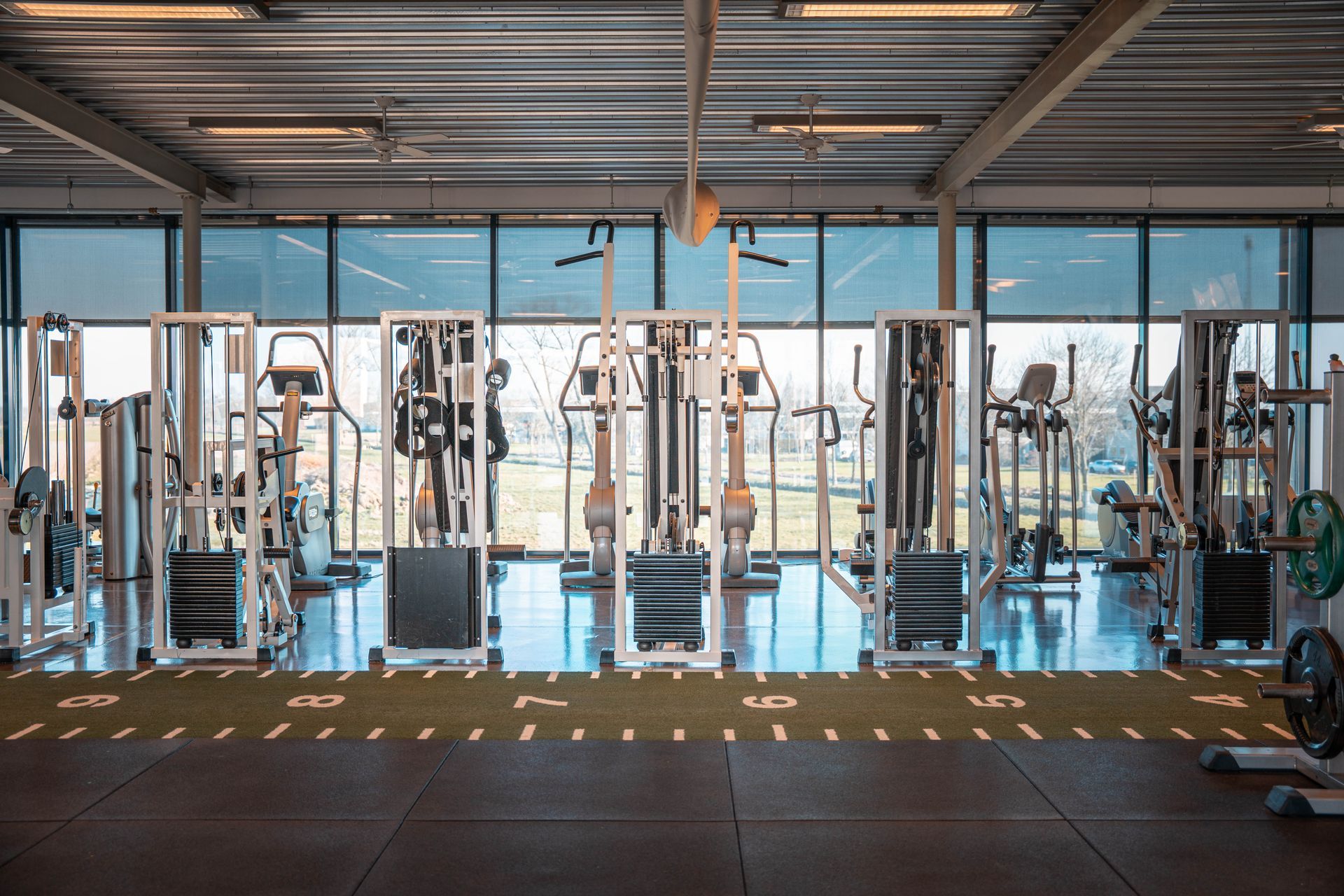 Een grote lege sportschool met veel fitnessapparatuur.