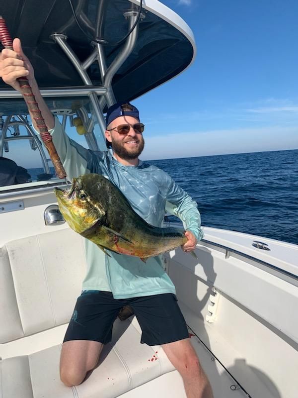 A man is holding a fish on a boat in the ocean.