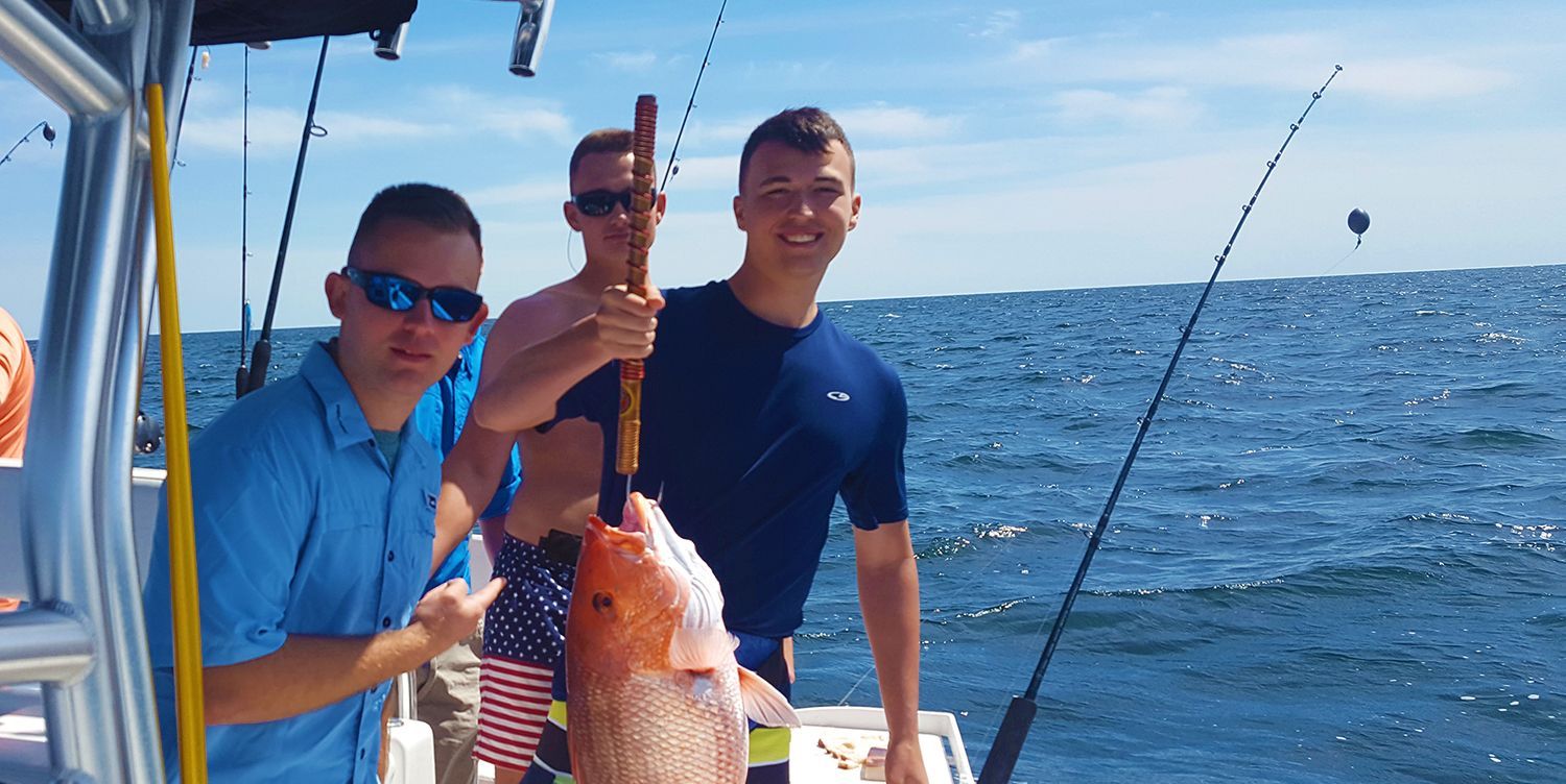 Three men are standing on a boat holding a large fish.