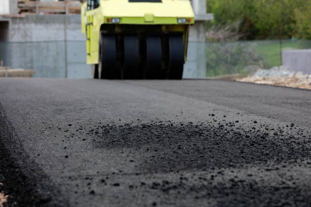 Road roller compacting fresh asphalt on a new road.