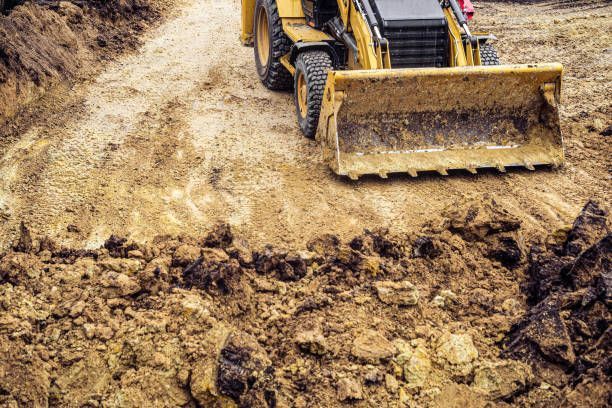 Yellow excavator scooping dirt on a construction site.