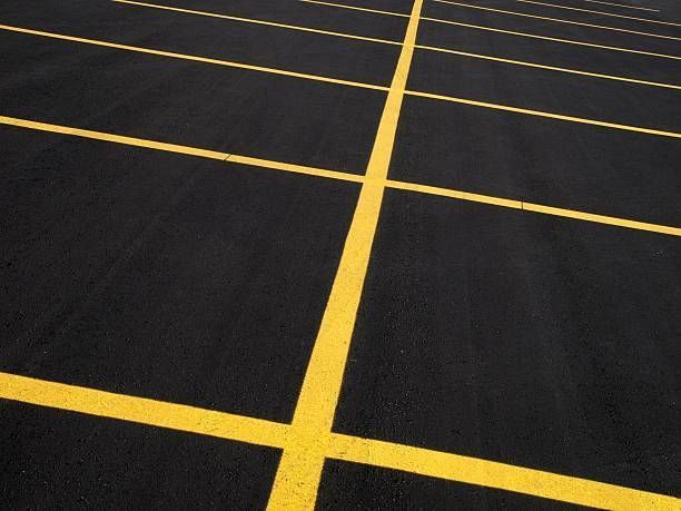 Black asphalt parking lot with yellow painted lines.