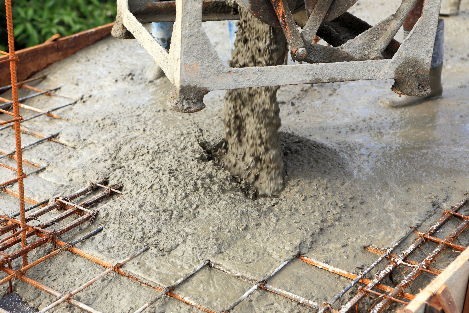 Pouring concrete onto rebar framework from a machine.