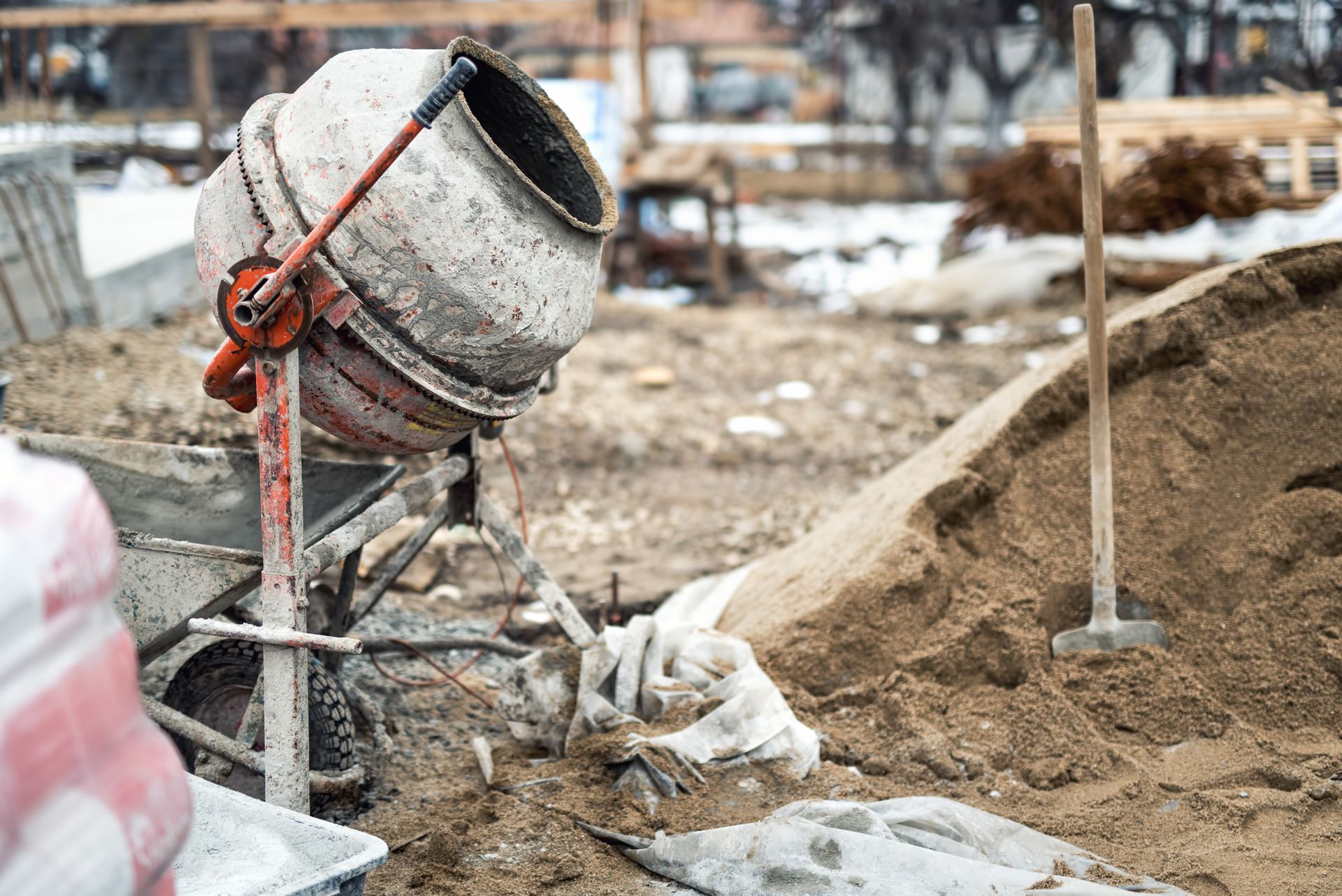 Cement mixer on a construction site with a pile of sand in the background.