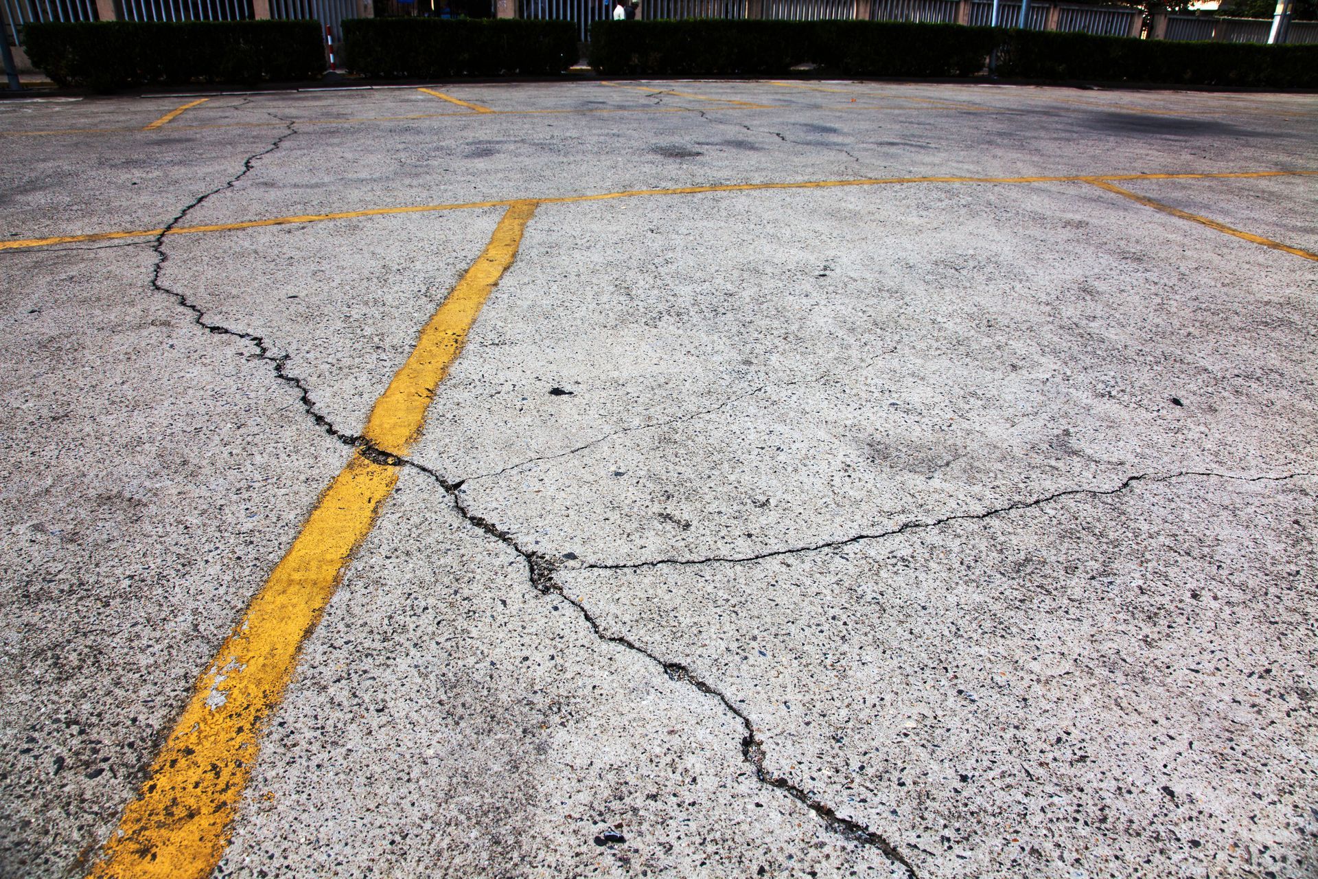 Cracked asphalt parking lot with yellow painted lines.