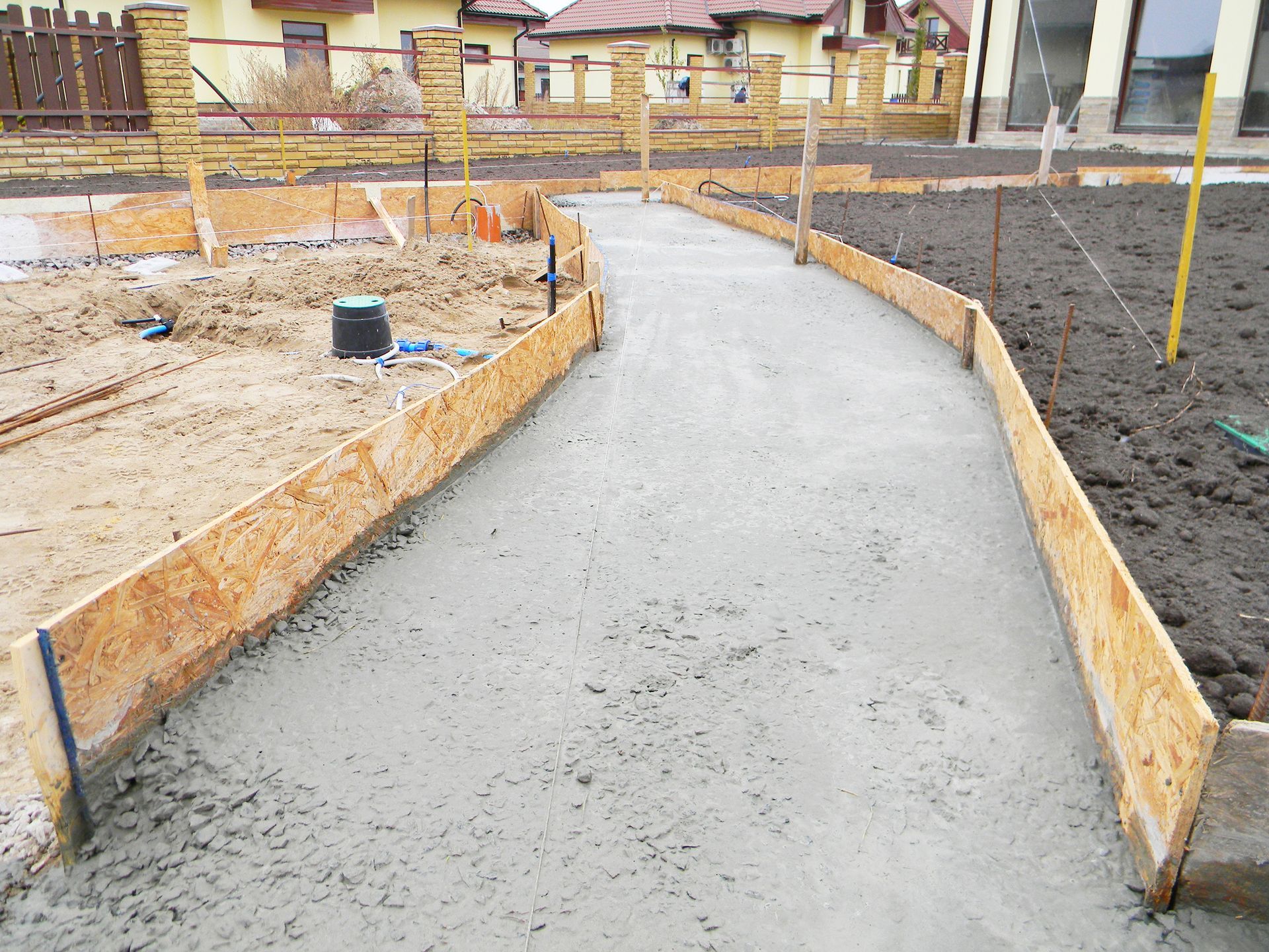 Freshly poured concrete pathway with wooden formwork, outdoors.