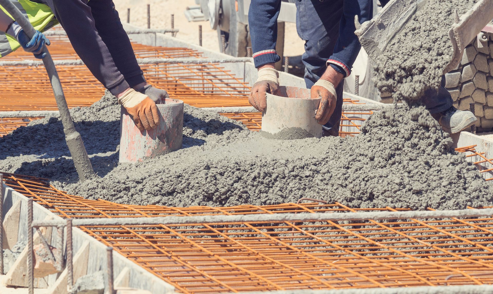 Workers pouring concrete into a form with rebar, construction site.