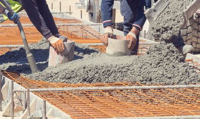 Workers pouring concrete into a form with rebar, construction site.